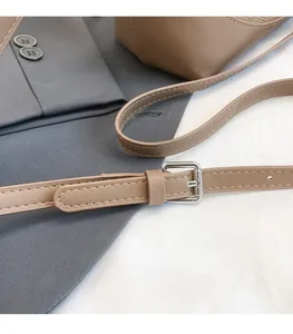Detail of brown leather strap with silver buckle and white stitching on a grey background