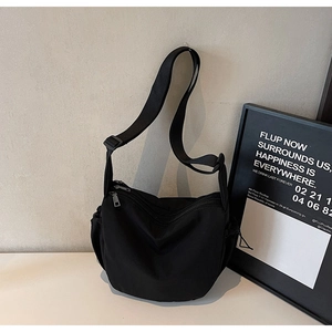 Detail of black large capacity nylon crossbody bag with adjustable wide strap and side pocket