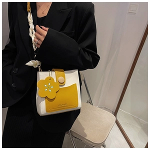 Detail of crossbody bag with yellow and white contrast, silk scarf, and flower charm