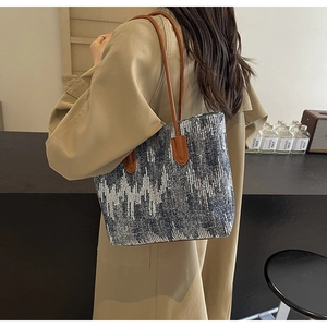 Detail of blue denim tote bag with silver sequin zigzag patterns and brown leather handles
