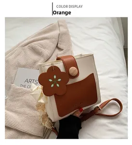 Detail view of mini two-tone crossbody bag with silk scarf and flower charm