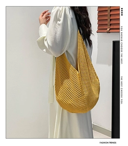 Detail of a bright yellow hand-knitted hobo shoulder bag with summer floral mesh pattern