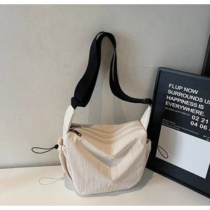 Detail of off-white multi-pocket nylon crossbody bag with black strap and zippers