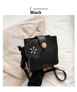 Detail of black mini bucket bag with wood texture round buckle and floral charm accessory