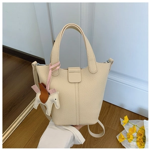 Close-up of beige lychee texture bucket bag with horse charm and adjustable shoulder strap