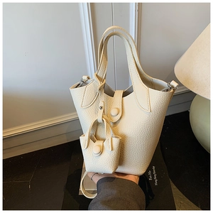 Detailed macro view of the cream white litchi pattern leather bucket bag and mini pouch charm