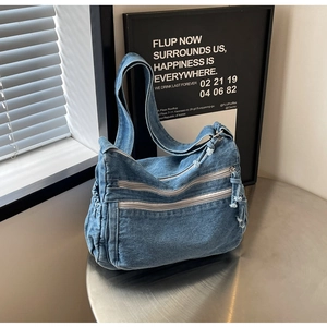 Detail view of denim shoulder bag featuring multi-zipper pockets and vintage blue fabric