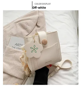 Detail of off-white mini crossbody bag featuring a wooden buckle and flower leather pendant