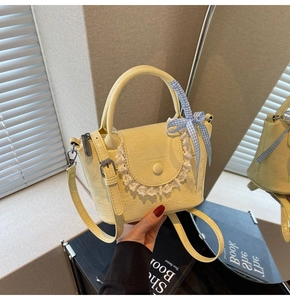 Détail du mini sac seau avec dentelle, texture cuir et ruban à carreaux bleu et blanc