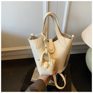 Close-up of cream lychee grain leather bucket bag with matching mini charm and silver hardware