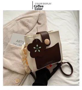 Detail of a chic cream and coffee crossbody bag with a floral charm and wooden button