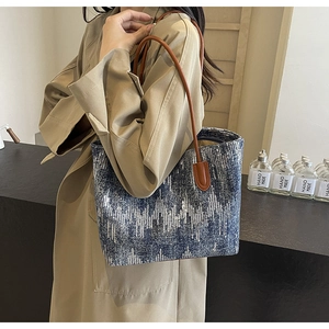 Detail of blue and white geometric denim tote bag with brown leather handles and sequins