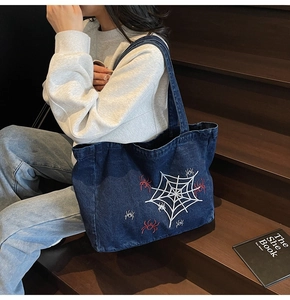 Detail of gothic spider web embroidery on a large blue denim tote bag for casual wear