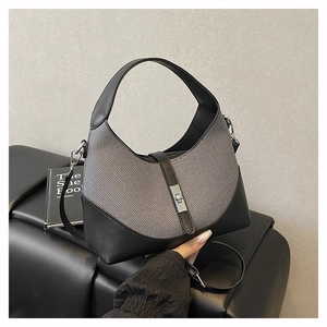 Detailed view of half-moon bag with black leather stitching and metal twist lock