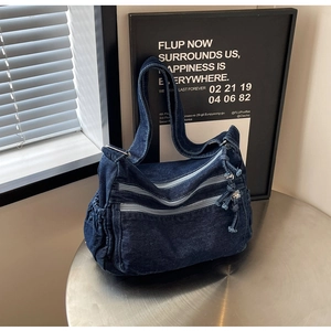 Detailed close-up of dark blue denim tote bag with dual zipper pockets and side pockets
