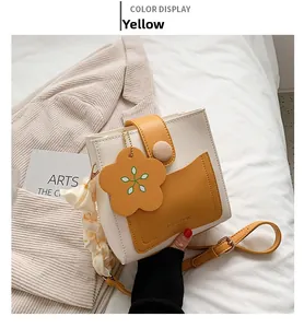 Detail of color-block mini square bag with flower charm and wooden buckle accent