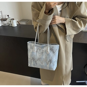Detail of blue and silver sequin tote bag texture styled with a khaki trench coat