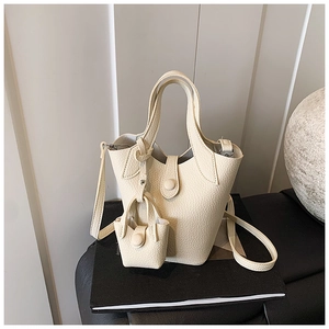 Close-up of beige lychee grain bucket bag with round buckle and mini pendant