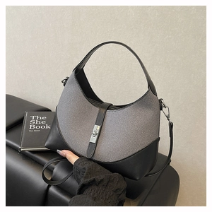 Detail shot of the two-tone woven fabric handbag featuring a metallic twist lock closure