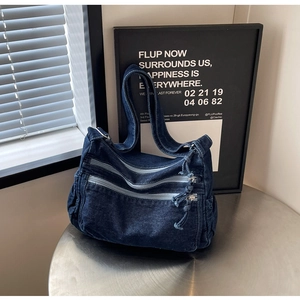 Detail of blue denim tote bag with multi-zipper pockets and wide shoulder strap