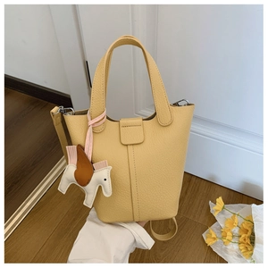 Detail of yellow lychee grain leather bucket bag with top handles and horse charm