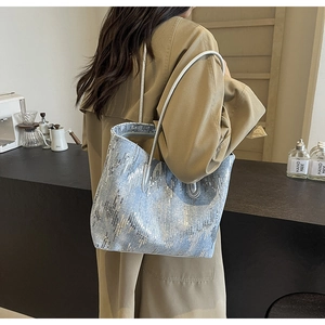 Close-up of a sequin tote bag in light blue with silver metallic straps and glossy finish