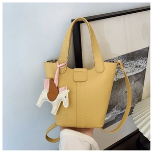 Detail of yellow lychee leather bucket bag with horse charm in modern home setting