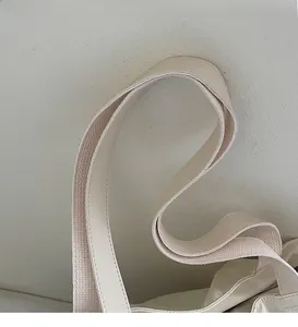 Close-up of the wide fabric and leather shoulder strap on this white canvas tote bag