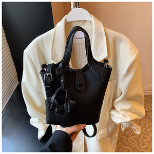 Close-up of black lychee grain leather bucket bag with mini charm and adjustable strap