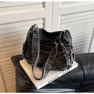 Detail of grey washed denim tote bag with multiple zippers and frayed edge textures