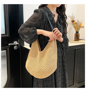 Detail of a beige knit shoulder bag with black leather strap on a floral dress