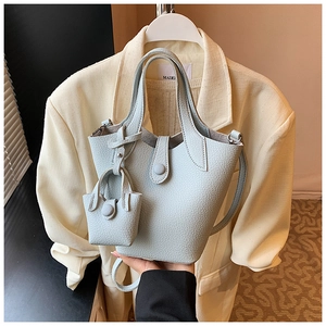 Detail of light blue bucket bag showing premium lychee grain leather and mini charm