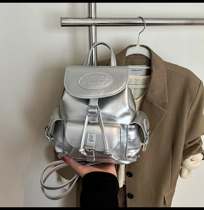 Detail of metallic silver bucket backpack with drawstring closure and oval metal logo