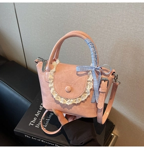 Vue détaillée du sac à main plissé rose avec bordures en dentelle et ruban à carreaux bleu