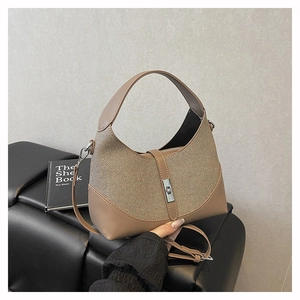 Detail of hobo bag with brown leather and beige woven texture featuring silver hardware