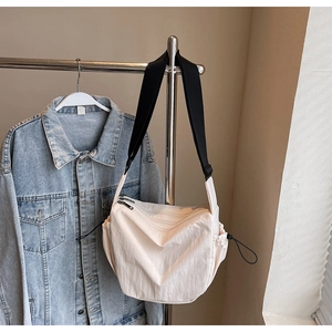 Detail view of cream canvas crossbody bag with adjustable strap and drawstring design