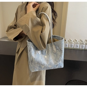 Detail showing shimmering sequins on a light blue denim tote bag with leather straps
