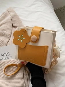 Minimalist beige and yellow leather crossbody box bag with floral charm and wood buckle