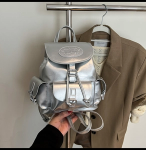 Detail of silver metallic backpack with buckle pockets and polished mirror finish texture