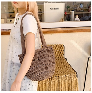 Detail view of deep brown hollow crochet tote bag worn by a model in a cozy cafe