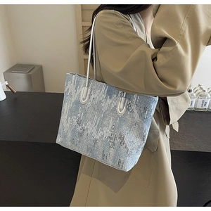 Detail of blue denim tote bag with silver sequins and metallic shoulder straps