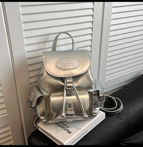 Detail of a shiny silver backpack with metallic PU texture and multiple pocket buckles