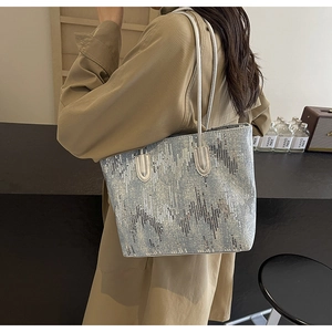 Detail shot of light blue sequined tote bag with silver straps and wavy textured pattern