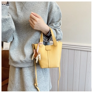 Detail of yellow lychee grain leather bucket bag with horse charm and slim shoulder strap