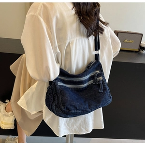 Detail view of the multi-pocket blue denim crossbody bag with adjustable wide canvas strap