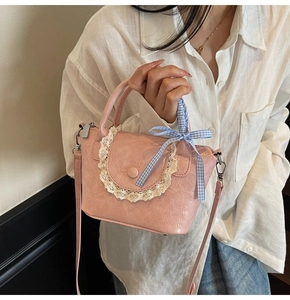 Détail du sac seau rose froncé avec bordure en dentelle et nœud à carreaux bleu