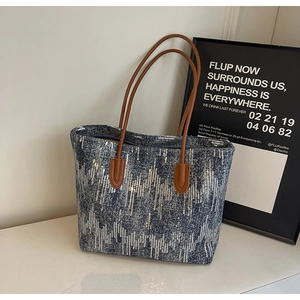 Detail of blue denim tote bag with silver sequins and brown leather handles