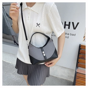 Detail of color-block grey and black handbag with silver metal rotary clasp and top handle