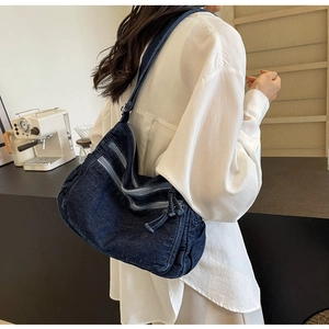 Detail view of large denim shoulder bag with three zippers and retro casual style