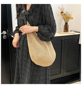 Close-up of beige woven tote bag with hollow mesh pattern and black shoulder straps